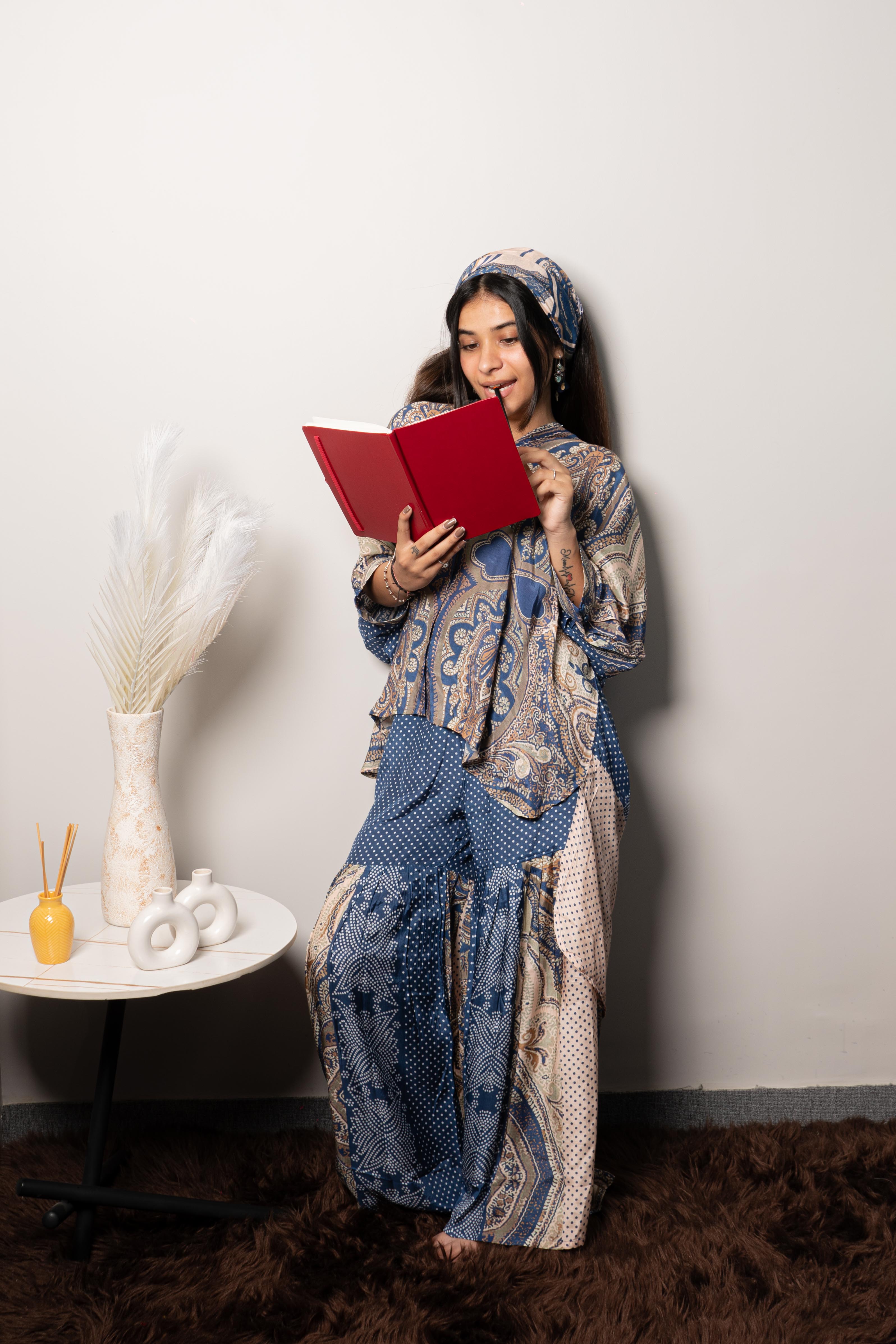 A woman sitting on a bench wearing a blue and purple abstract printed muslin silk co ord set with a shirt collar.