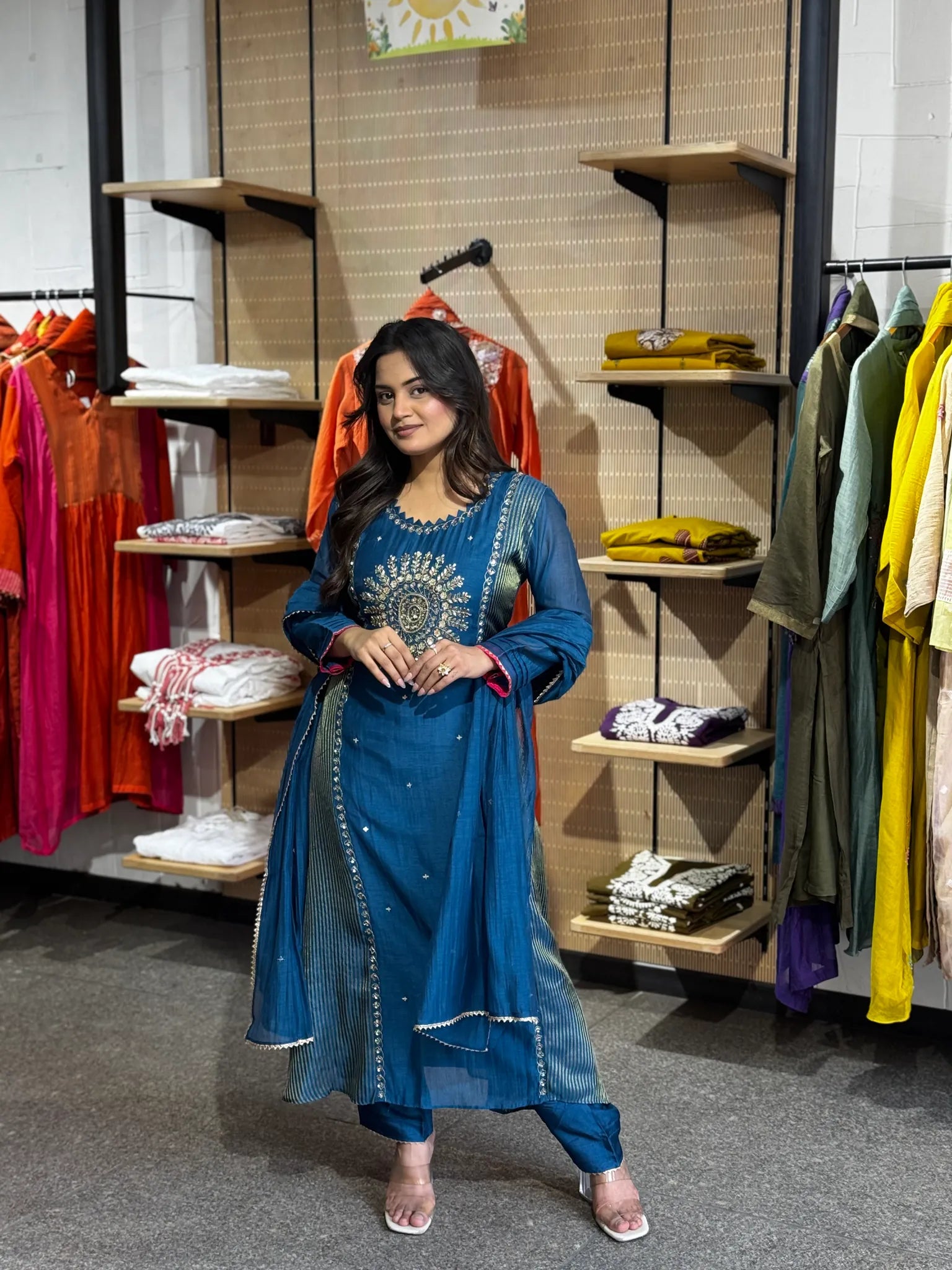 Full-length petrol-blue set, model mid-step, the sheer dupatta falling past the knee over a straight-cut kurta.