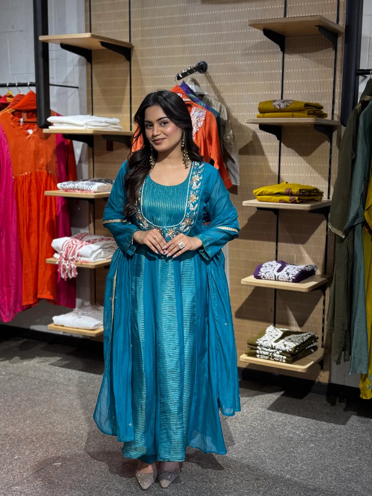 Turquoise A-line kurta shot with fine gold stripes, an embroidered floral yoke and sheer dupatta falling at her side.