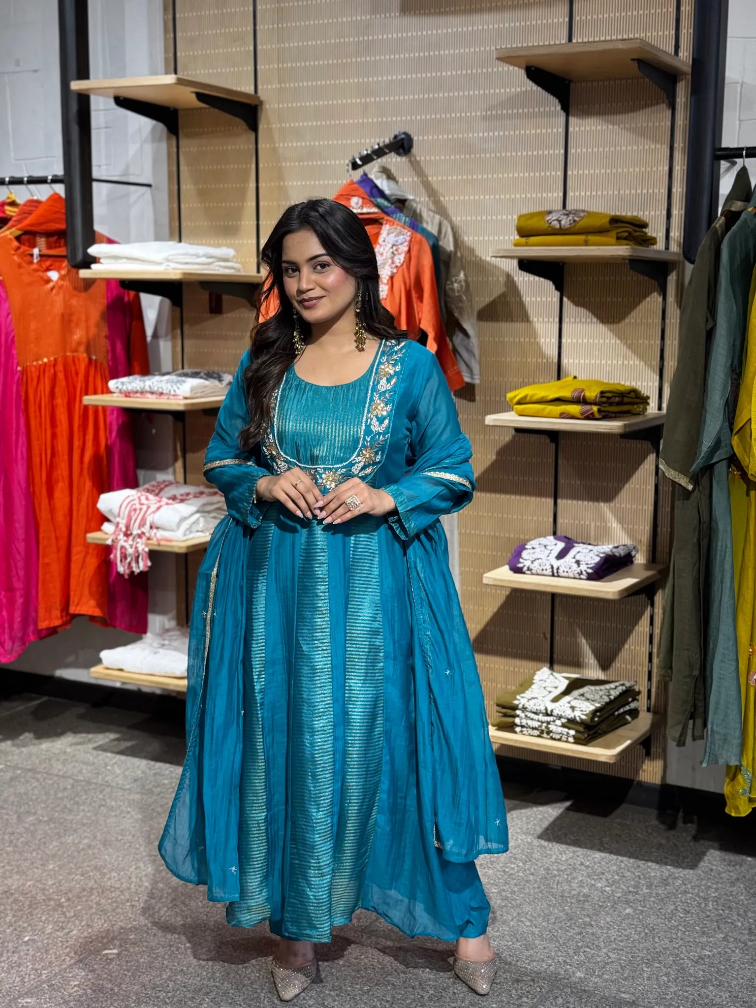 Full-length turquoise set, the dupatta looped over one shoulder and the pleated bodice flaring into a wide skirt.