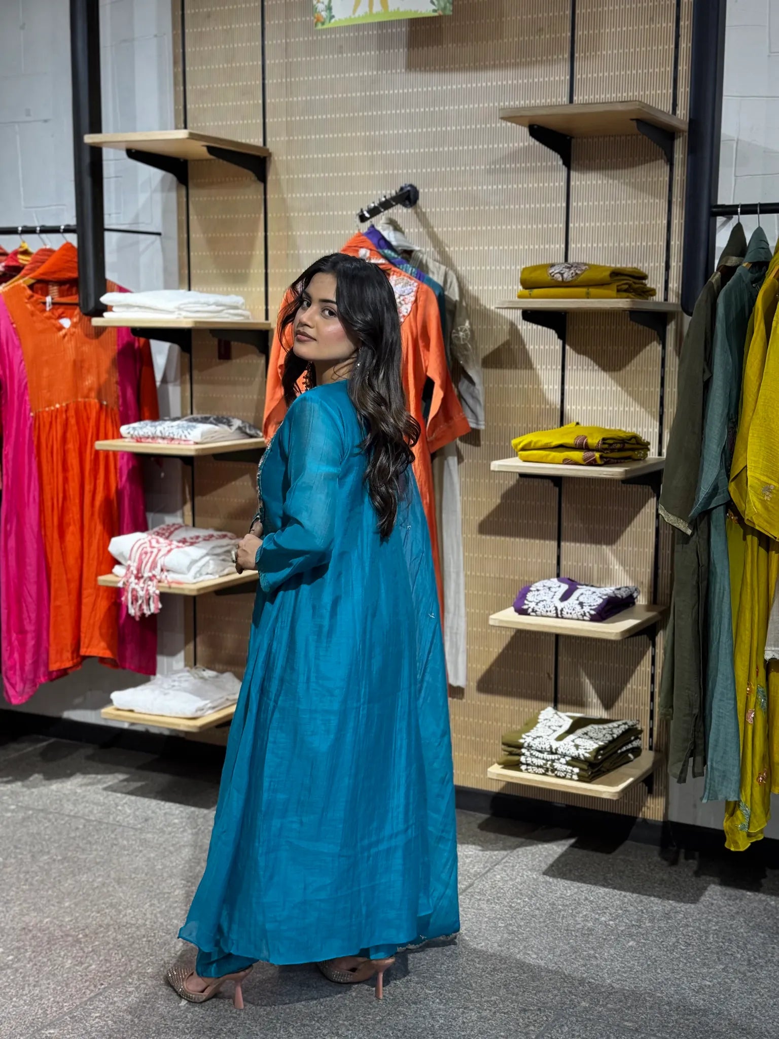 Rear three-quarter view in turquoise, the dupatta falling down the back over the full sweep of the A-line skirt.