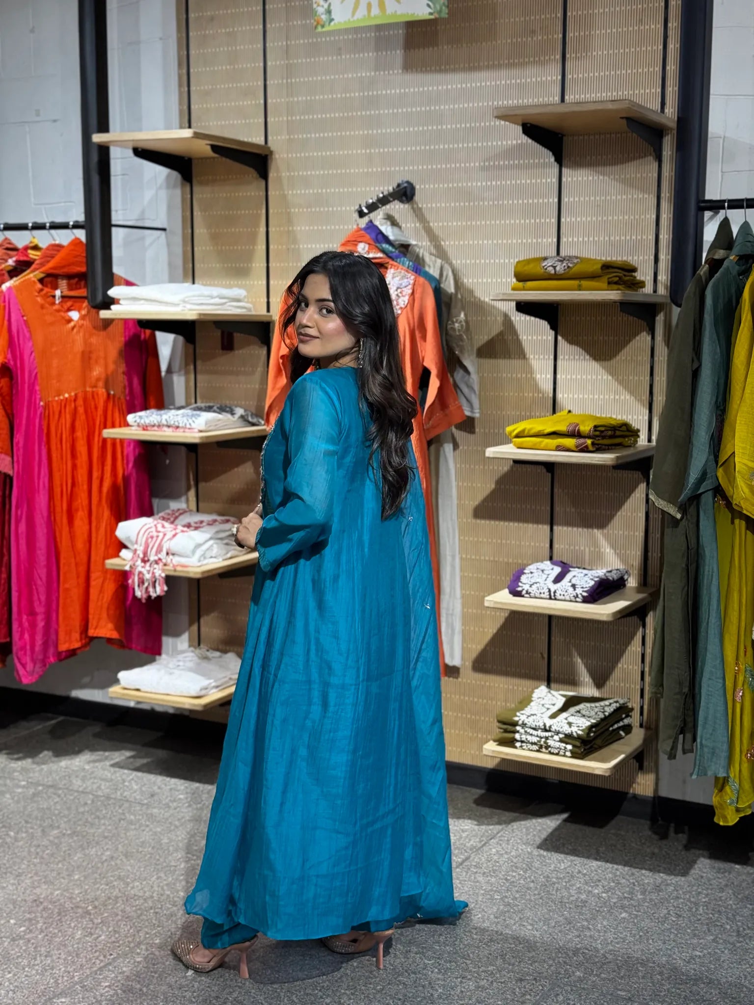 Side profile in the turquoise set, with the dupatta running long beside the gold-striped flare of the A-line skirt.