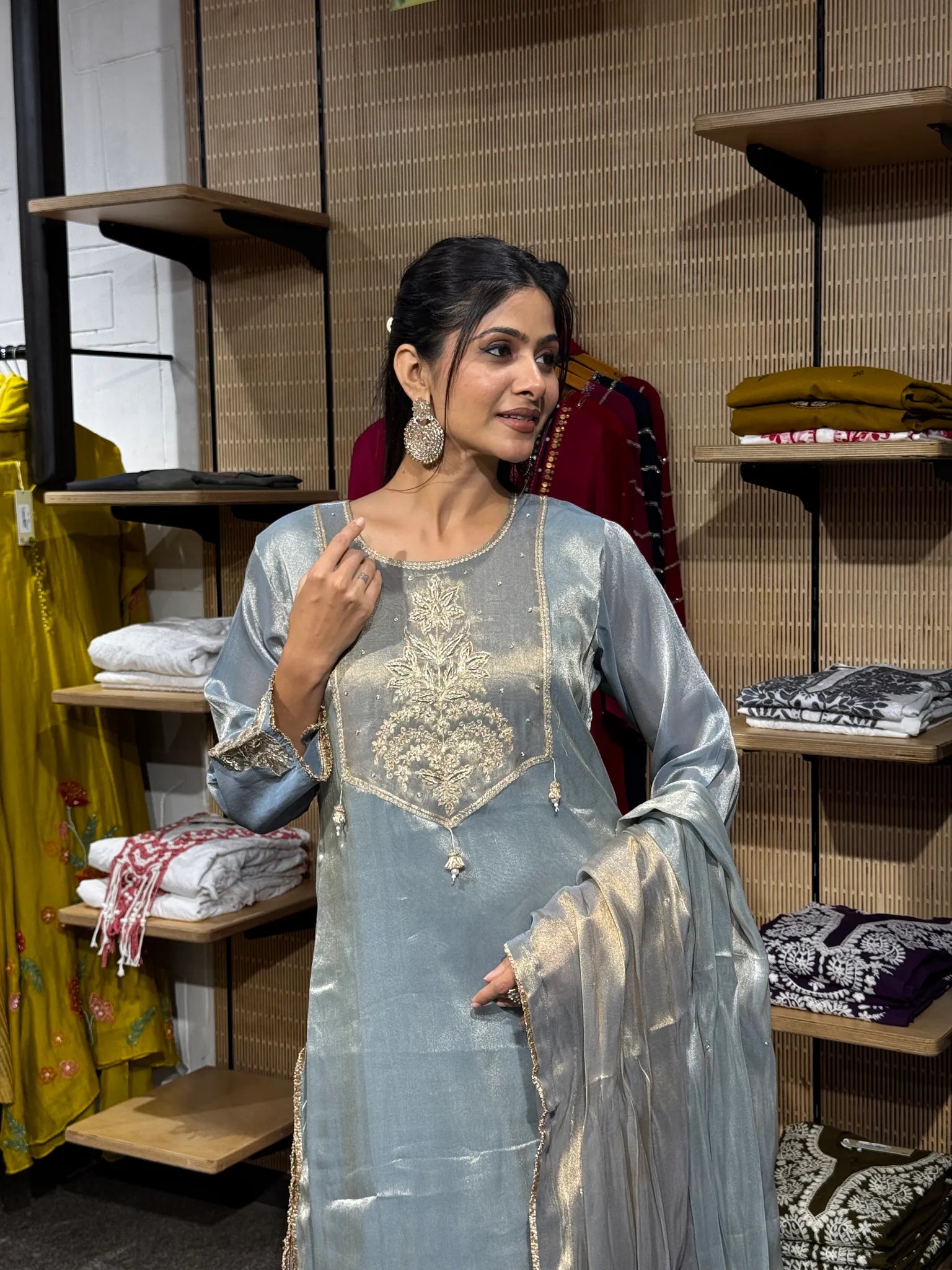 Close view of a woman in a pale blue tissue straight cut kurta with a gold embroidered centre motif, the dupatta over one arm.