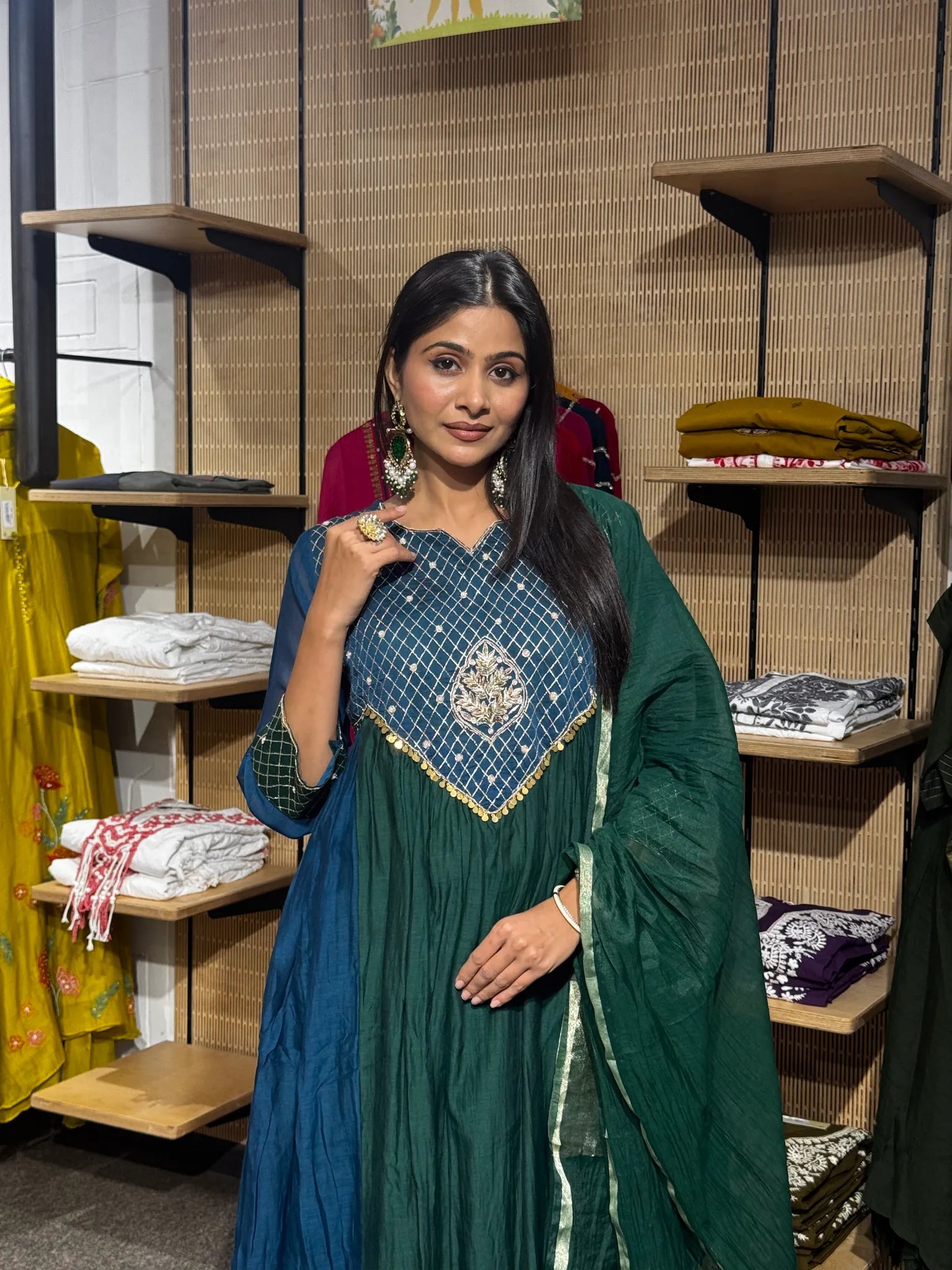 Close view of a teal mul chanderi A-line kurta with a checked brocade yoke and gold embroidered motif, worn with a green dupatta.