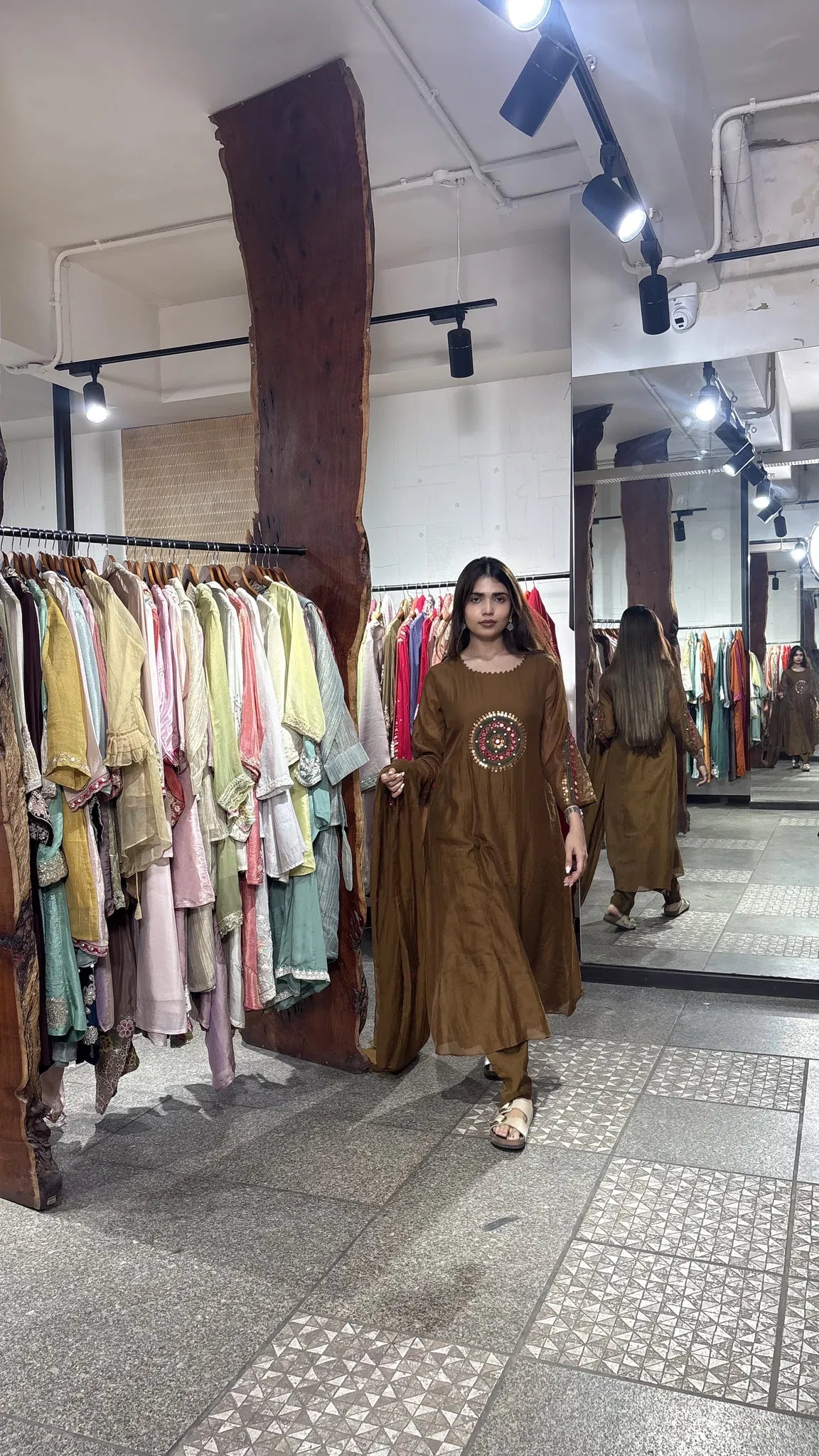Full-length walking shot of the brown mul chanderi A-line kurti set, the tobacco tone reading warm against the boutique floor.