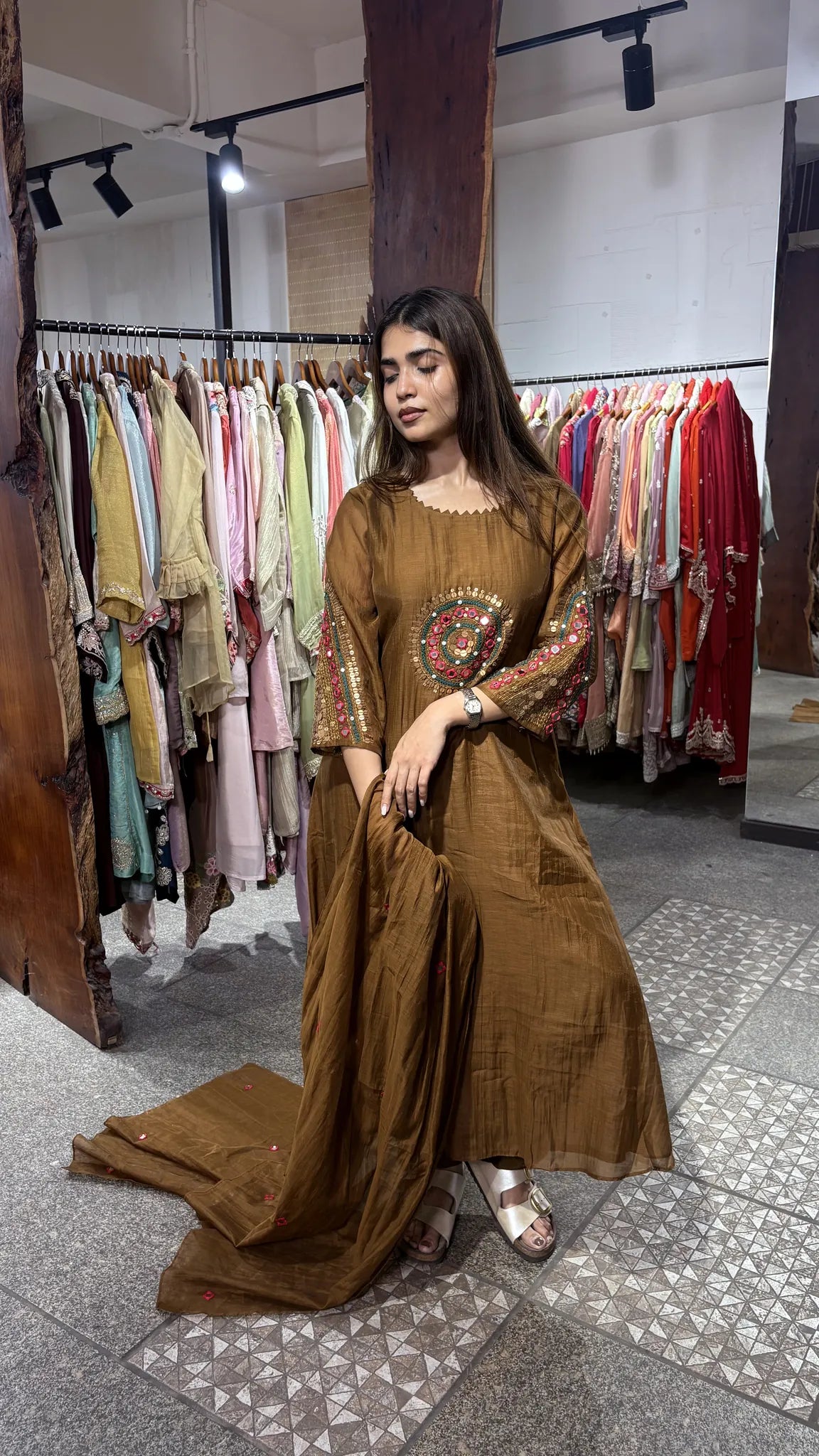 Front view of the brown mul chanderi kurti, with circular gold handwork at the chest and matching embroidery banding both cuffs.