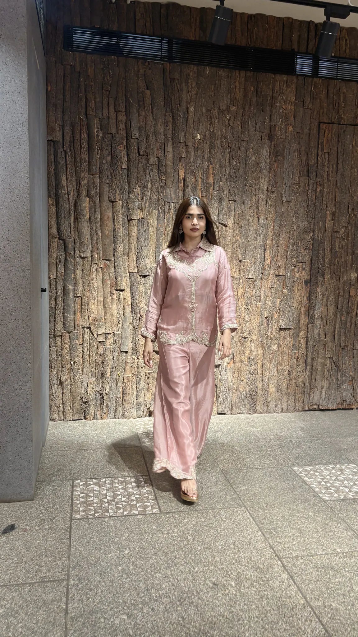 Full-length walking shot of the baby pink chinnon co-ord set, the wide plazo moving loosely over lace-trimmed hems.