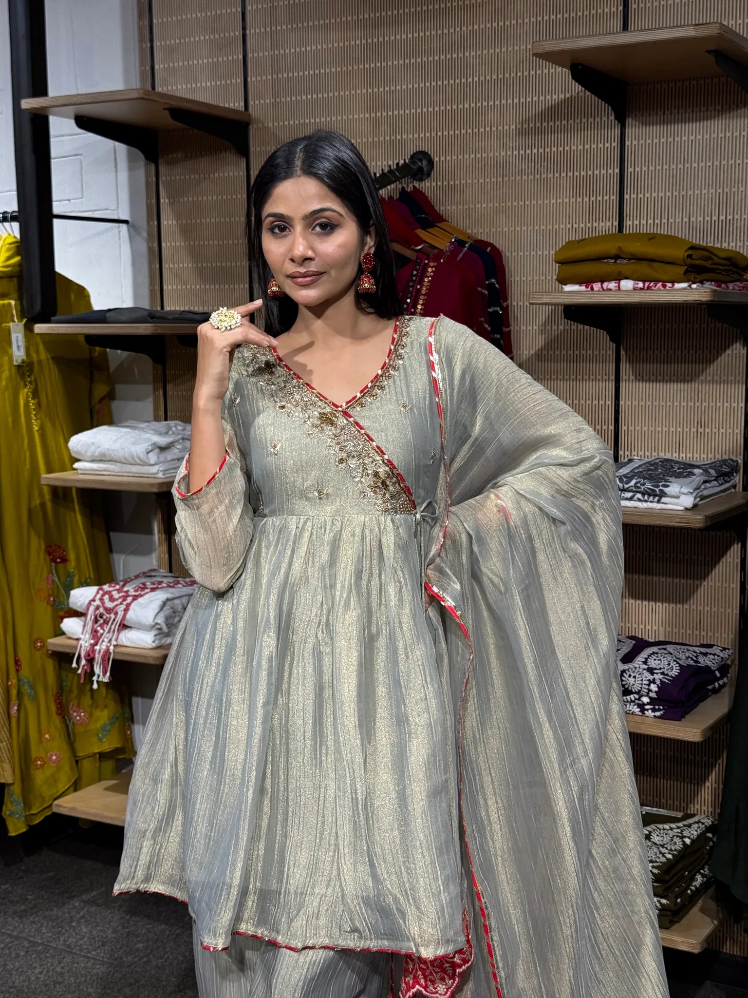 Close view of a cream tissue kediya top with a wrap neckline, red and gold embroidery, worn with a sheer red-bordered dupatta.