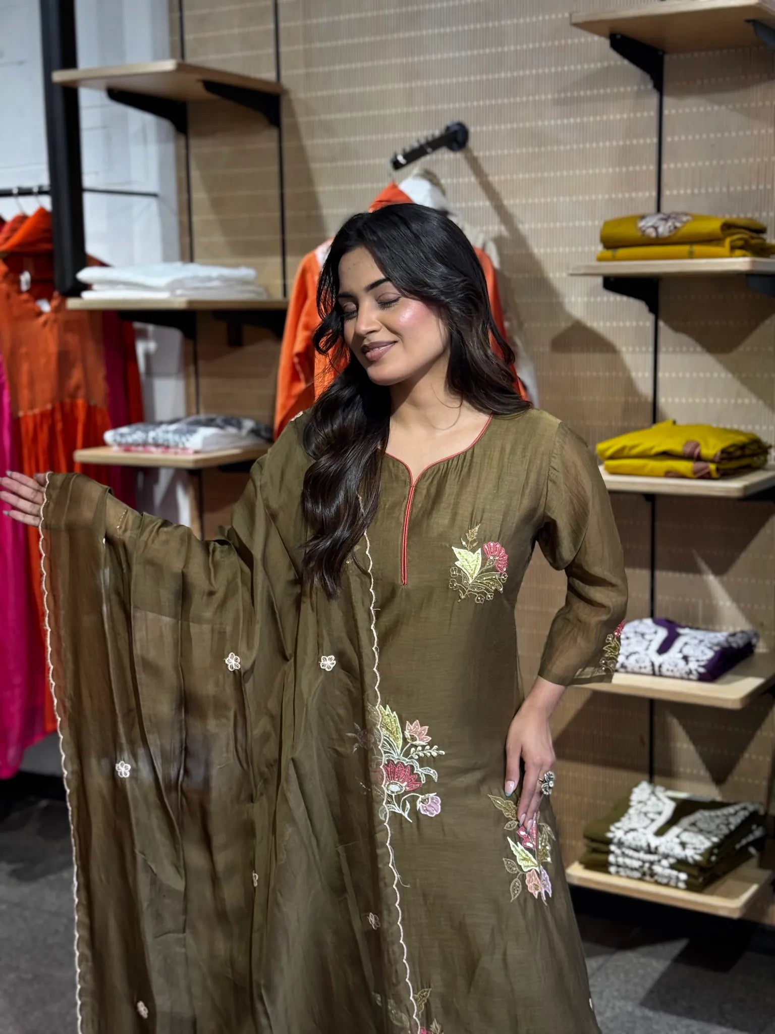Model holding the olive chanderi dupatta out at arm's length, floral embroidery across the chest and hem clearly visible.
