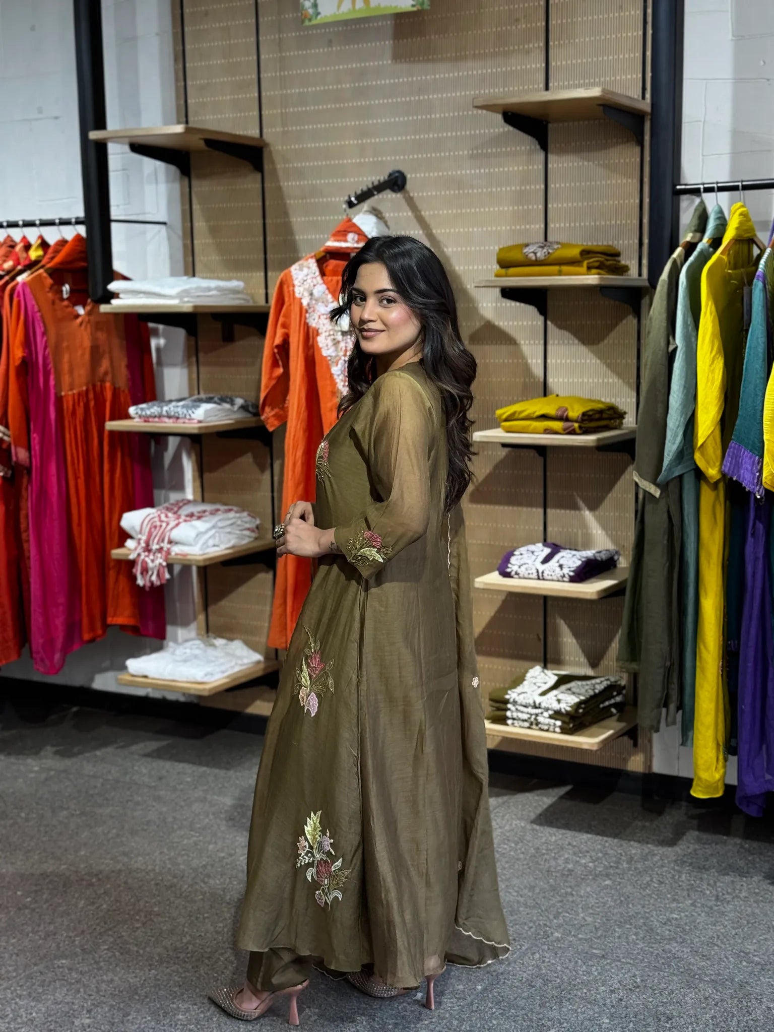 Side-on turn in the olive chanderi set, dupatta draped along the arm, embroidery visible at the hem of the flared kurta.