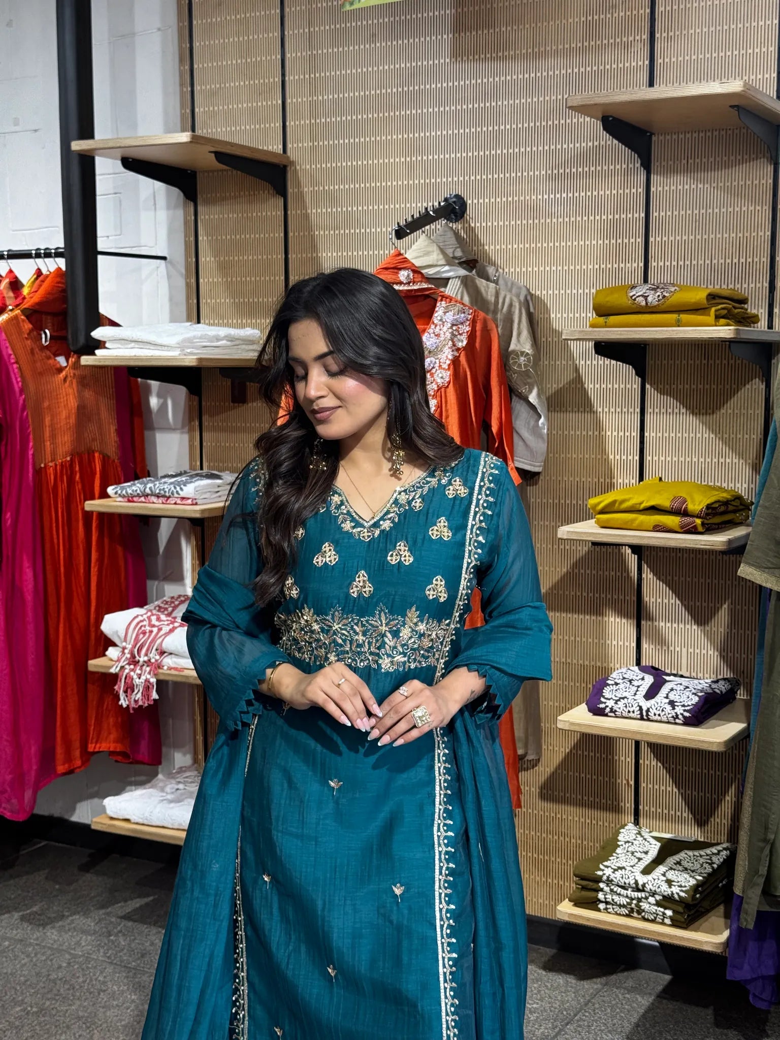 Waist-up in deep teal chanderi, gold thread motifs worked across the V-neck yoke and scattered as buti down the skirt.
