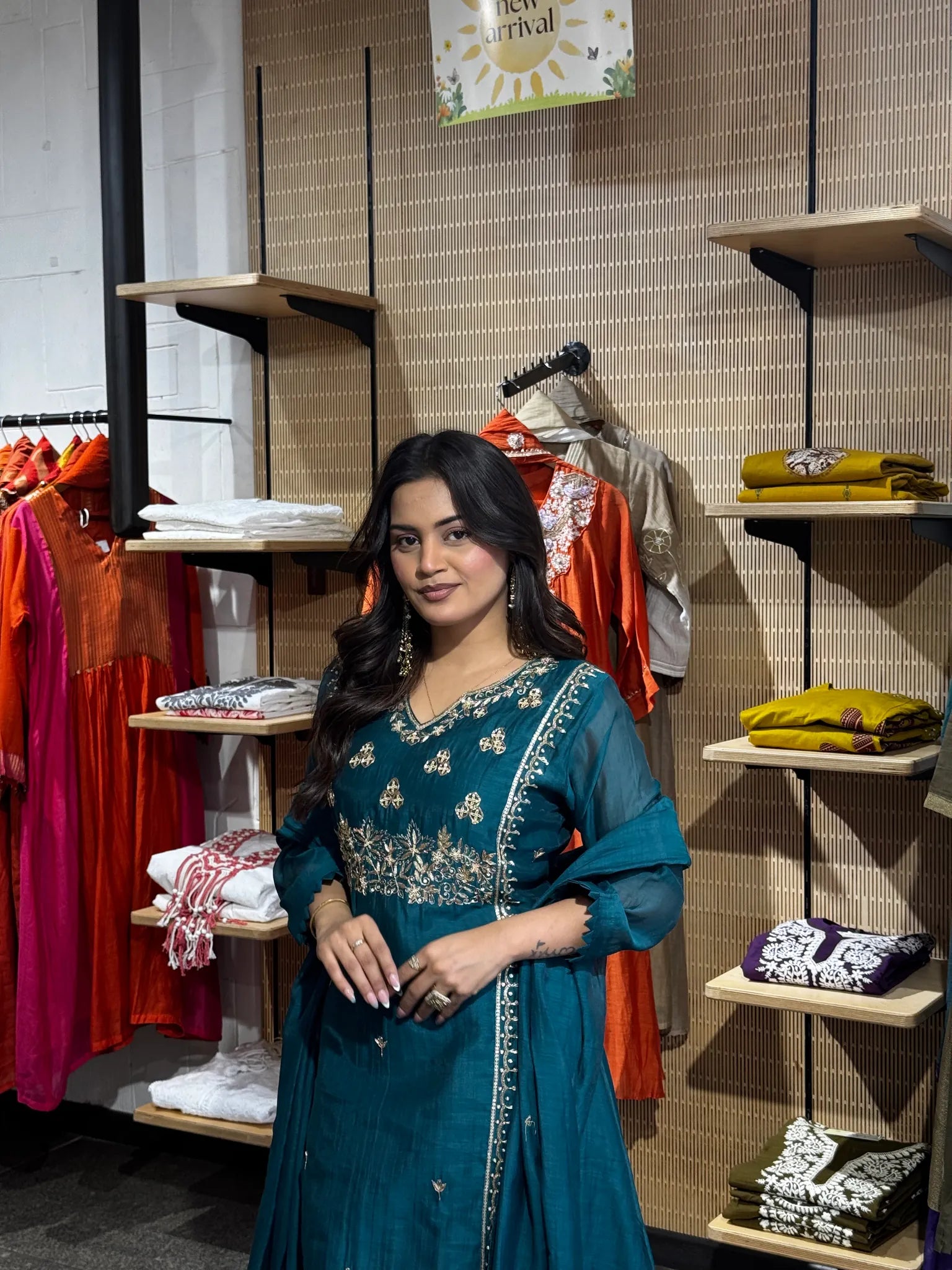 Model looking over her shoulder in the teal chanderi set, gold embroidery catching light at the neckline and cuff.