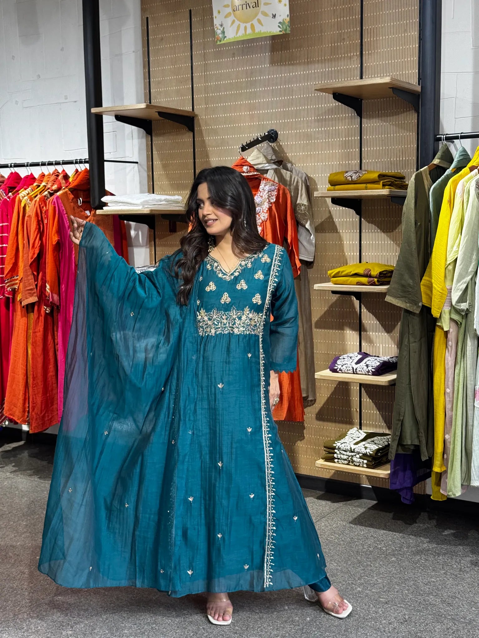 Model sweeping the sheer teal dupatta out to one side, gold buti scattered across its full width in the boutique.