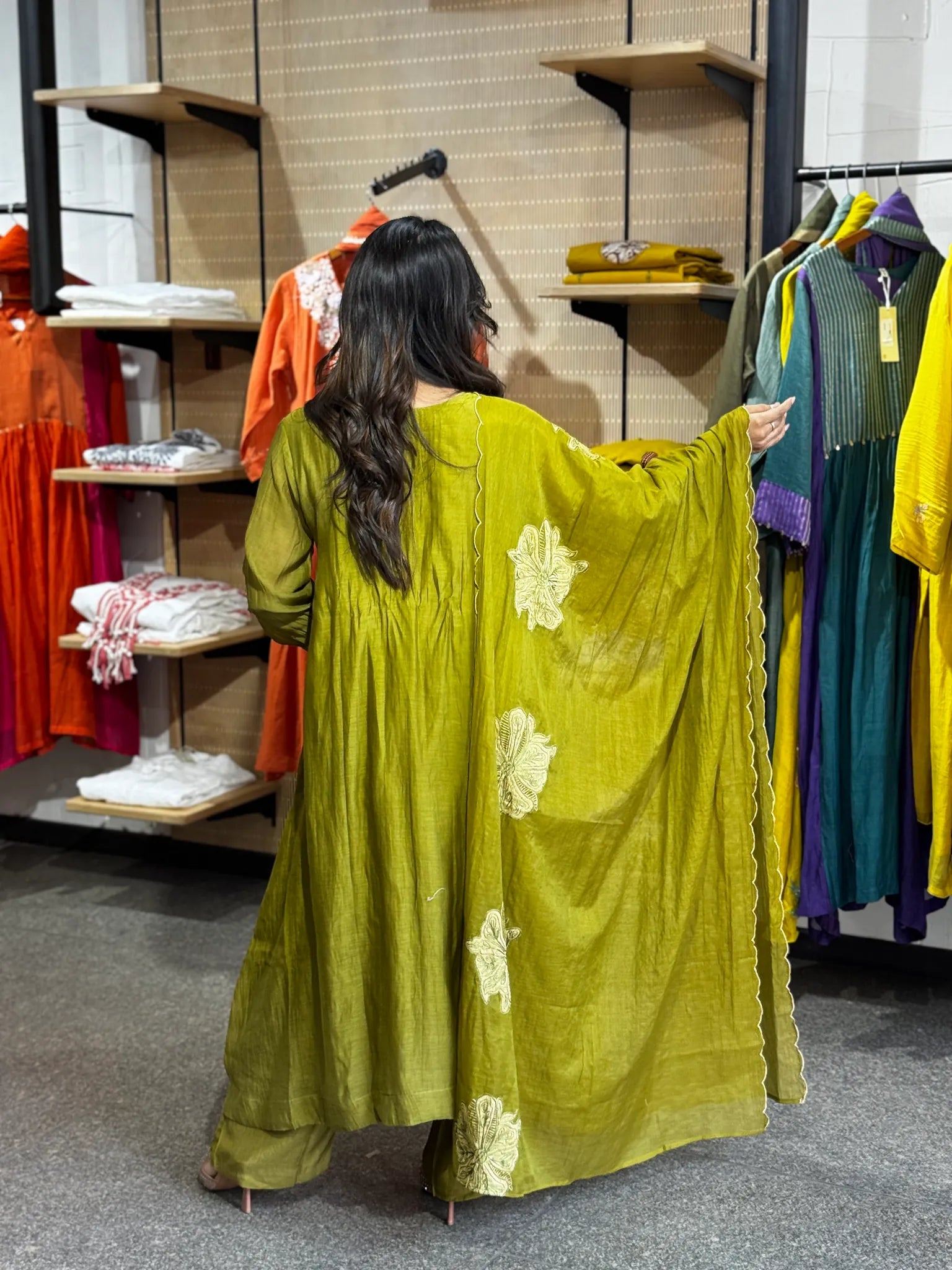 Back view of the mehendi green set, the dupatta held open to show the ivory blooms worked across its full width.