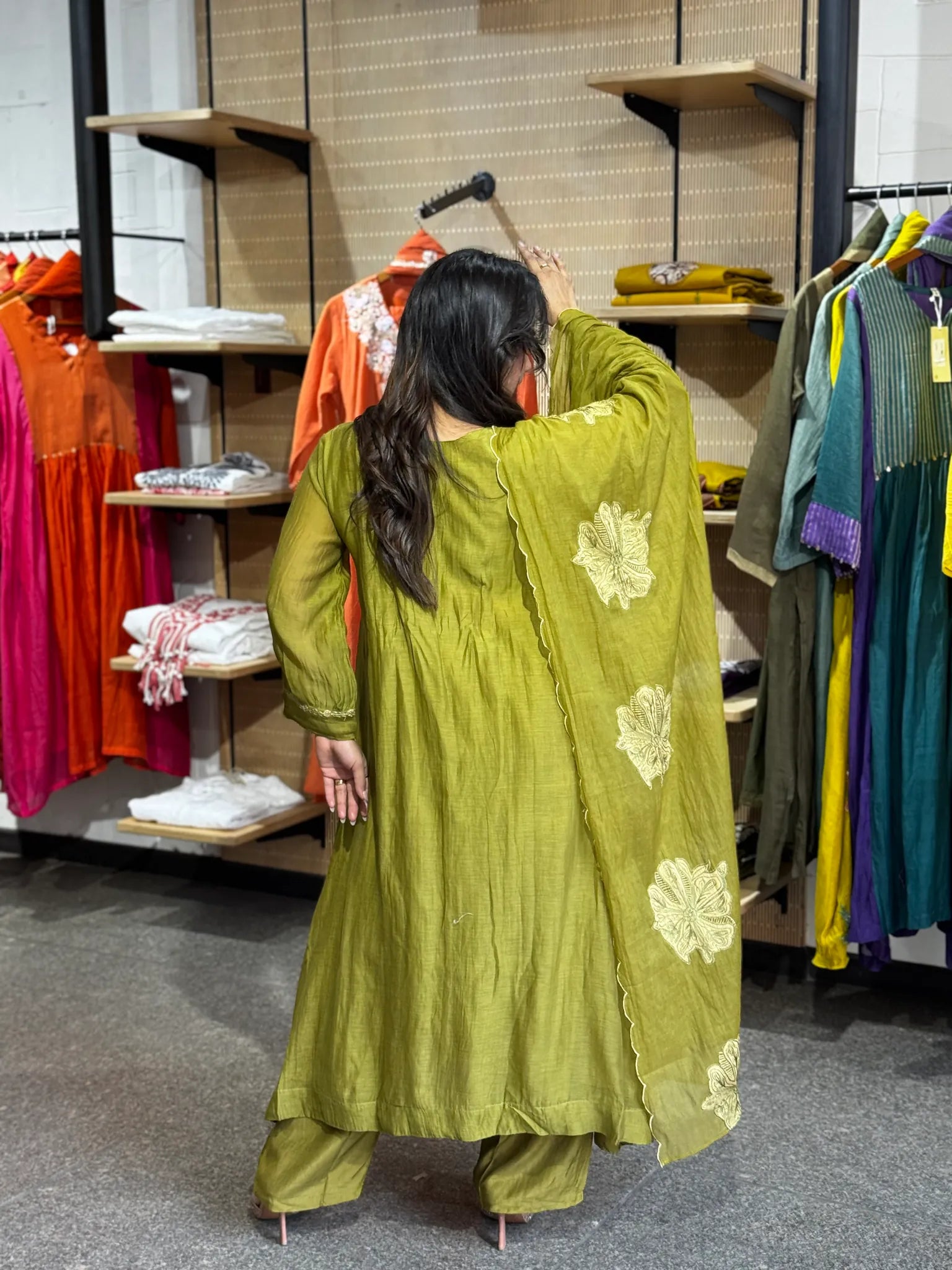 Rear view in mehendi chanderi, the dupatta falling down the back over the wide-legged matching palazzo trousers.