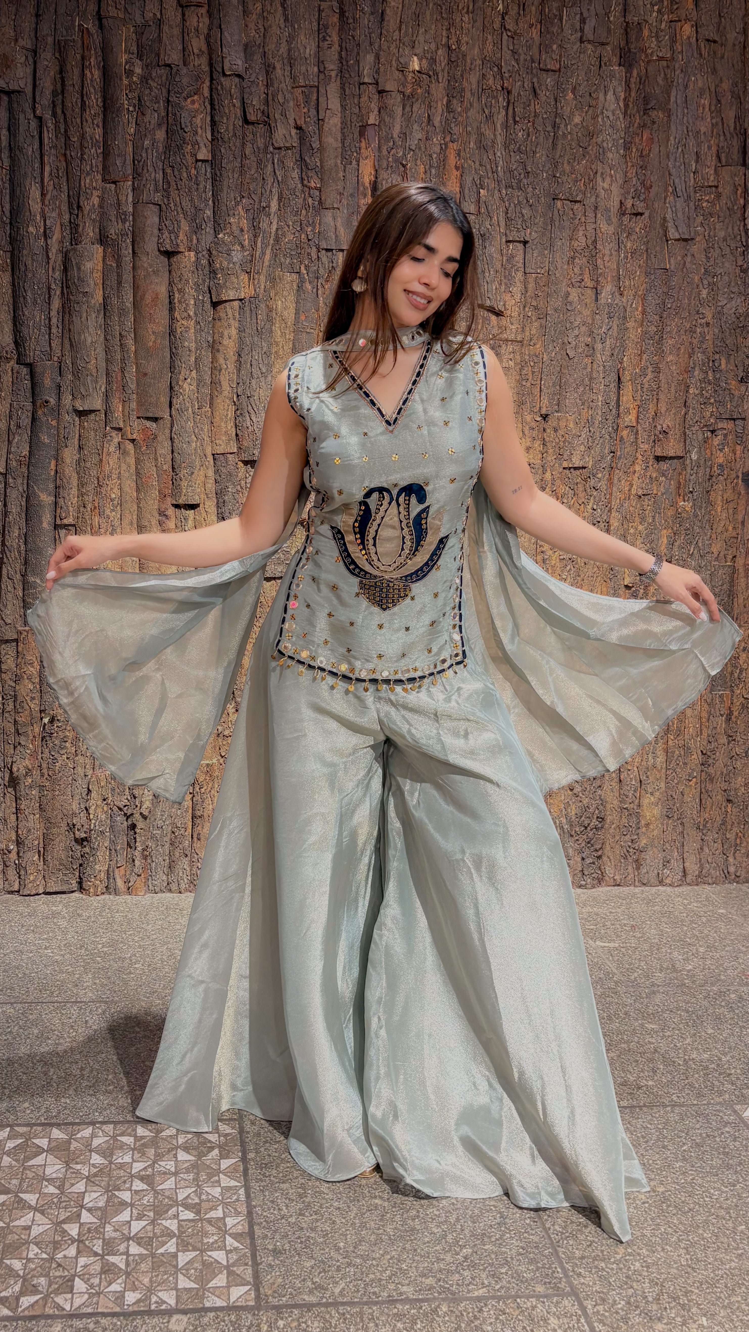 Mint green tissue plazo set with cape-style dupatta panels held wide, and a dark beaded lotus motif worked on the sleeveless top.