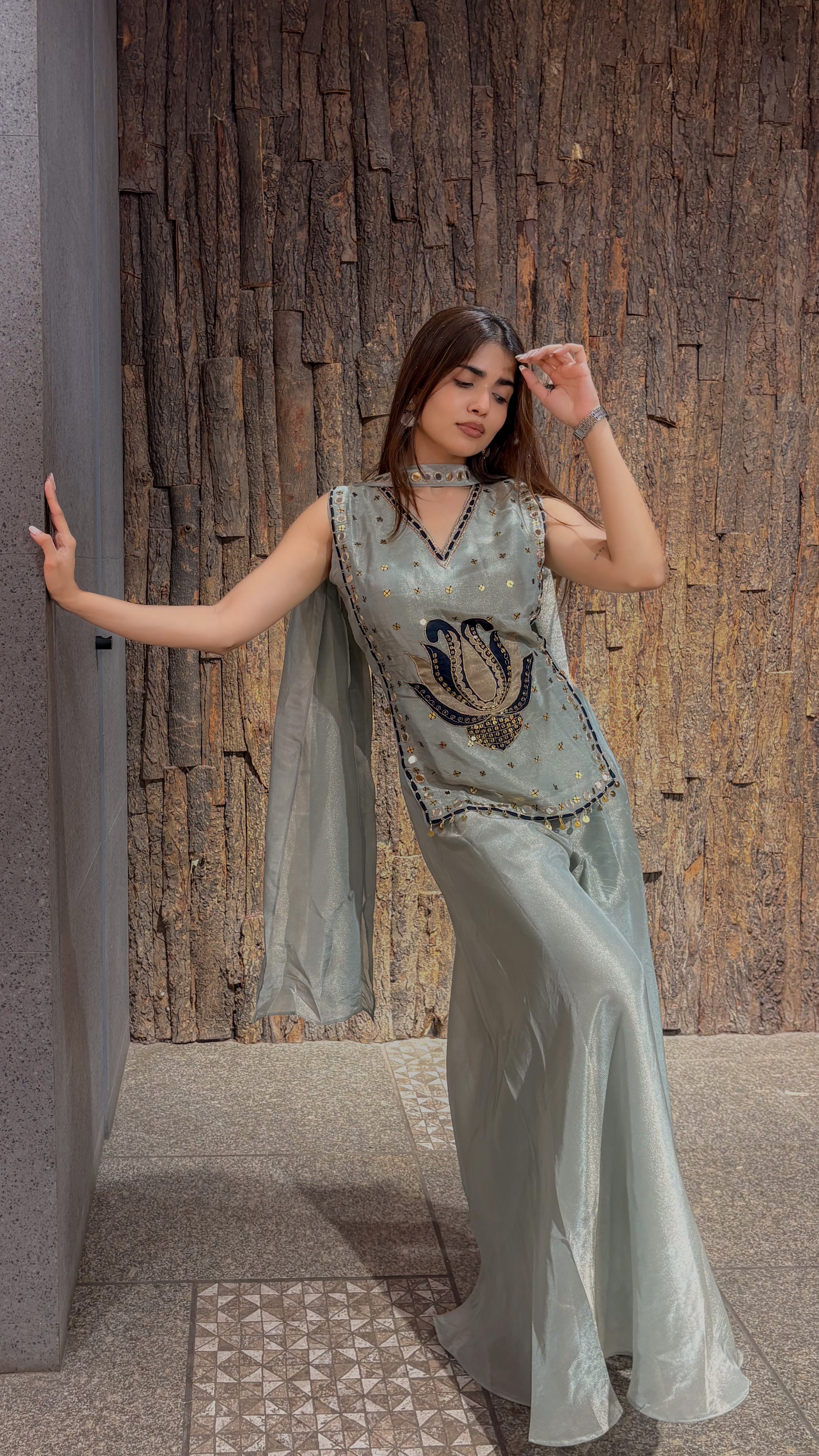 The mint green sleeveless top and wide tissue plazo seen against a stone pillar, showing the beaded edging along the neckline.