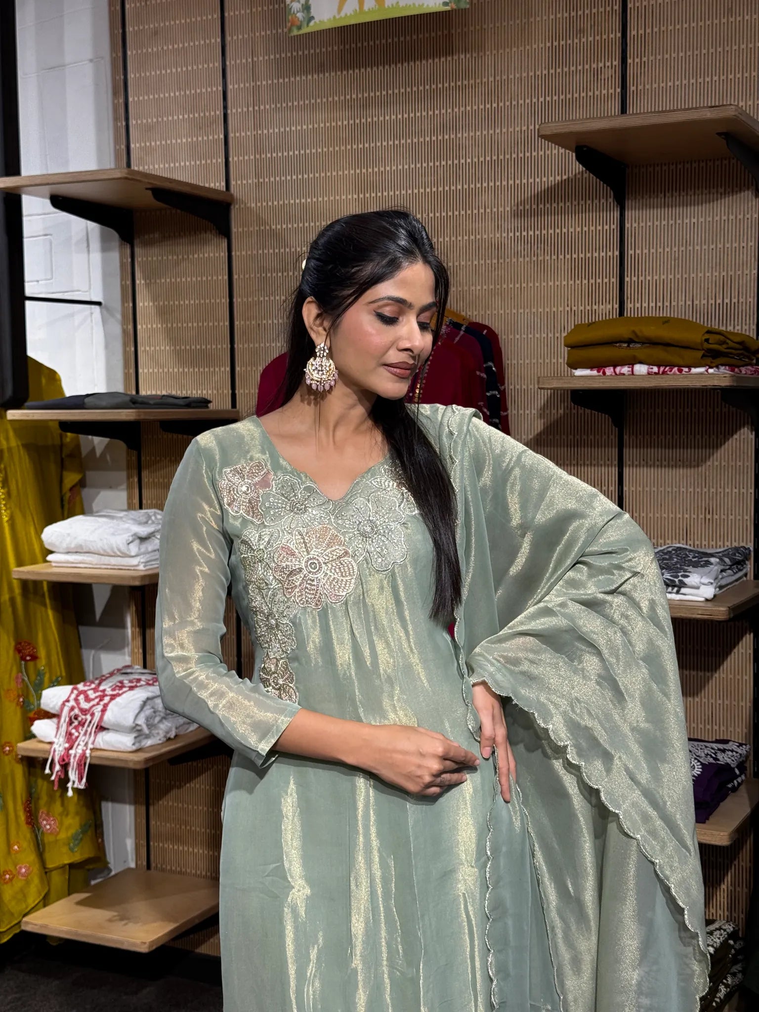 Close view of a woman in a mint green tissue kurta with a tonal thread and sequin embroidered V-neck yoke, the sheer dupatta draped over one arm.