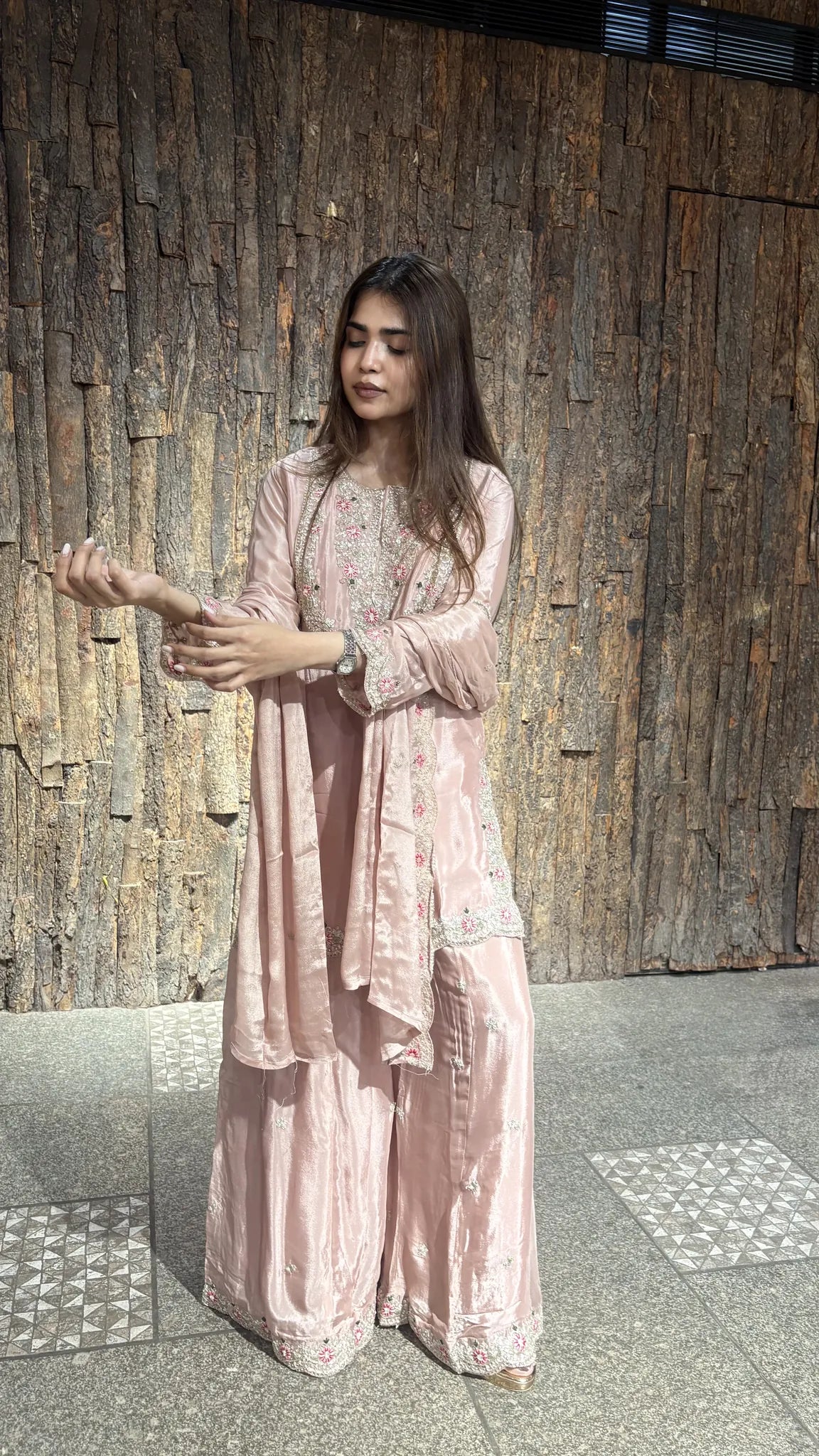 Side view of the dusty pink sharara suit, the dupatta draped long and the embroidered cuff detail visible at the wrist.