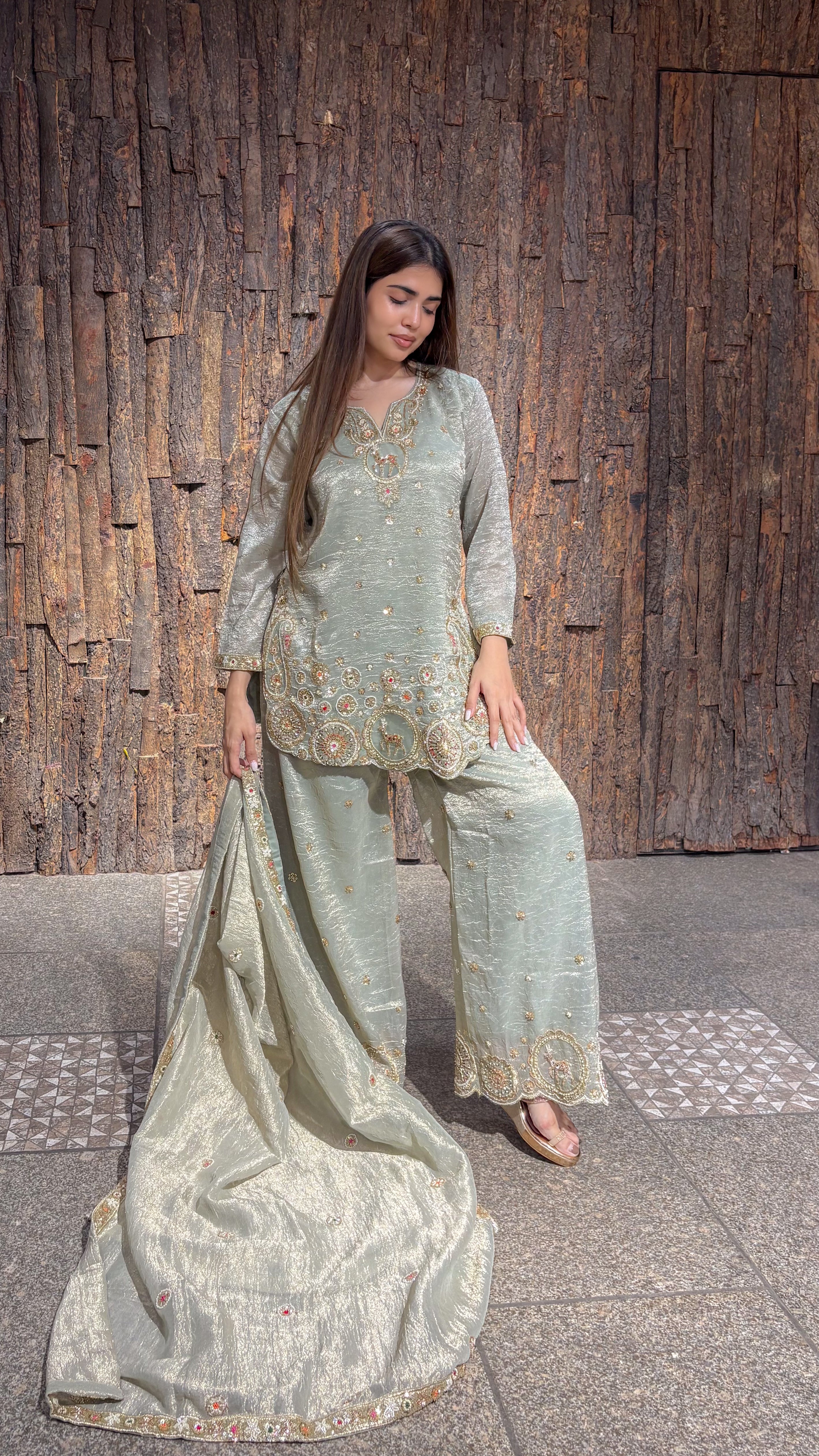 Side view of the pista green plazo set, the long tissue dupatta trailing on the floor behind the wide-legged trousers.