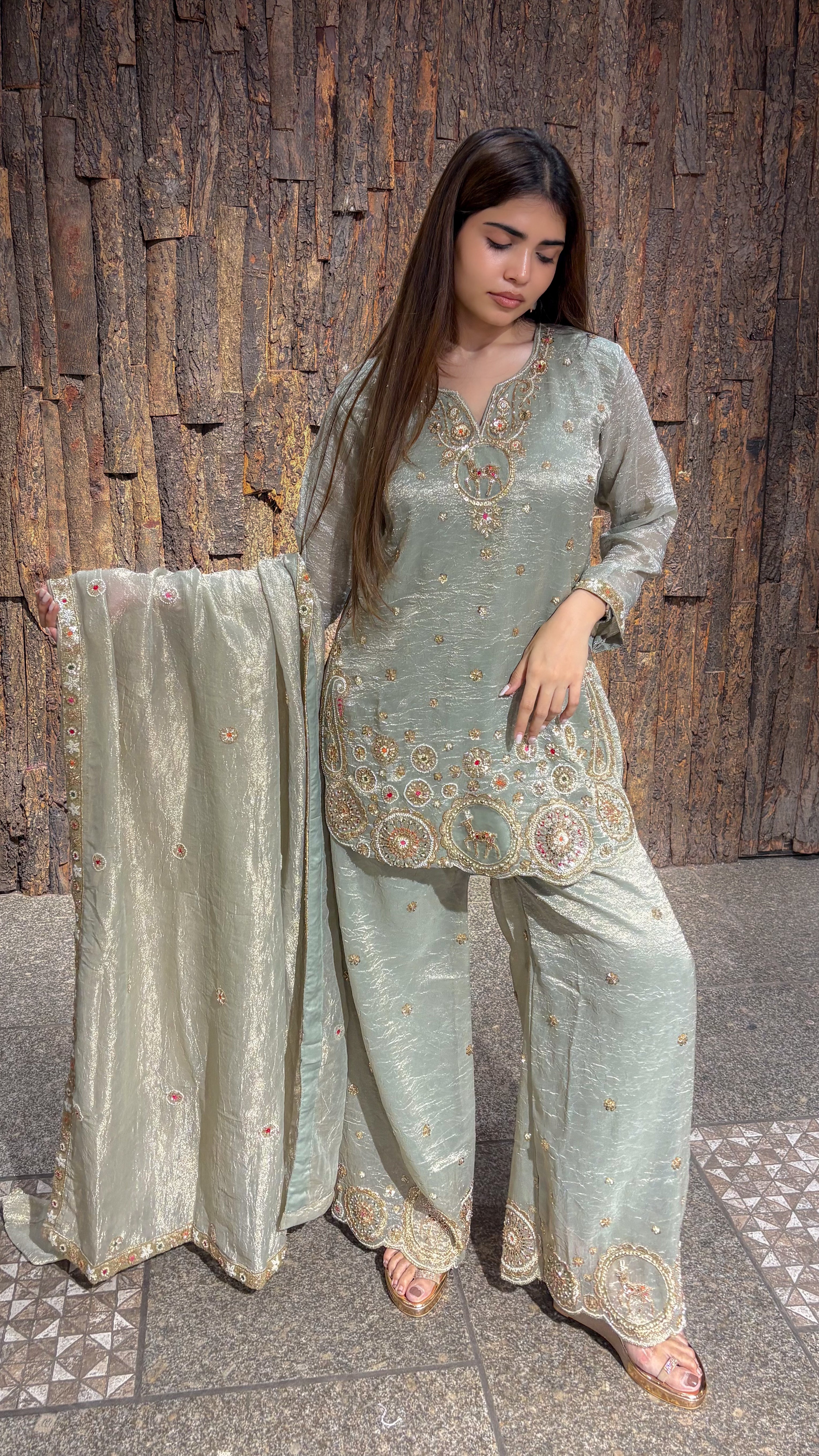 Side view of the pista green plazo set, the long tissue dupatta trailing on the floor behind the wide-legged trousers.