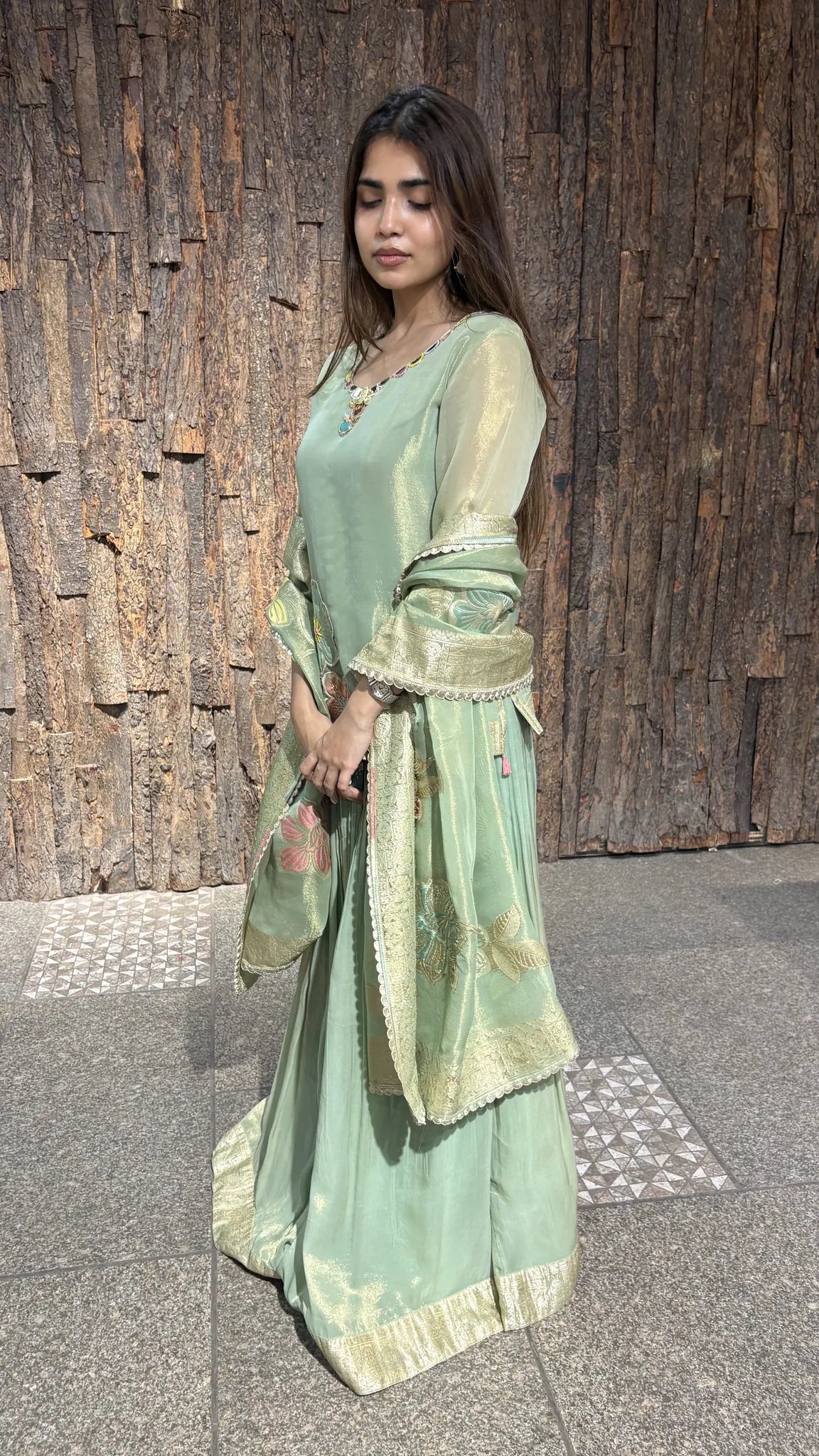 Side view of the pista green skirt set, showing how the tissue skirt falls to a gold-edged hem under the draped zari dupatta.