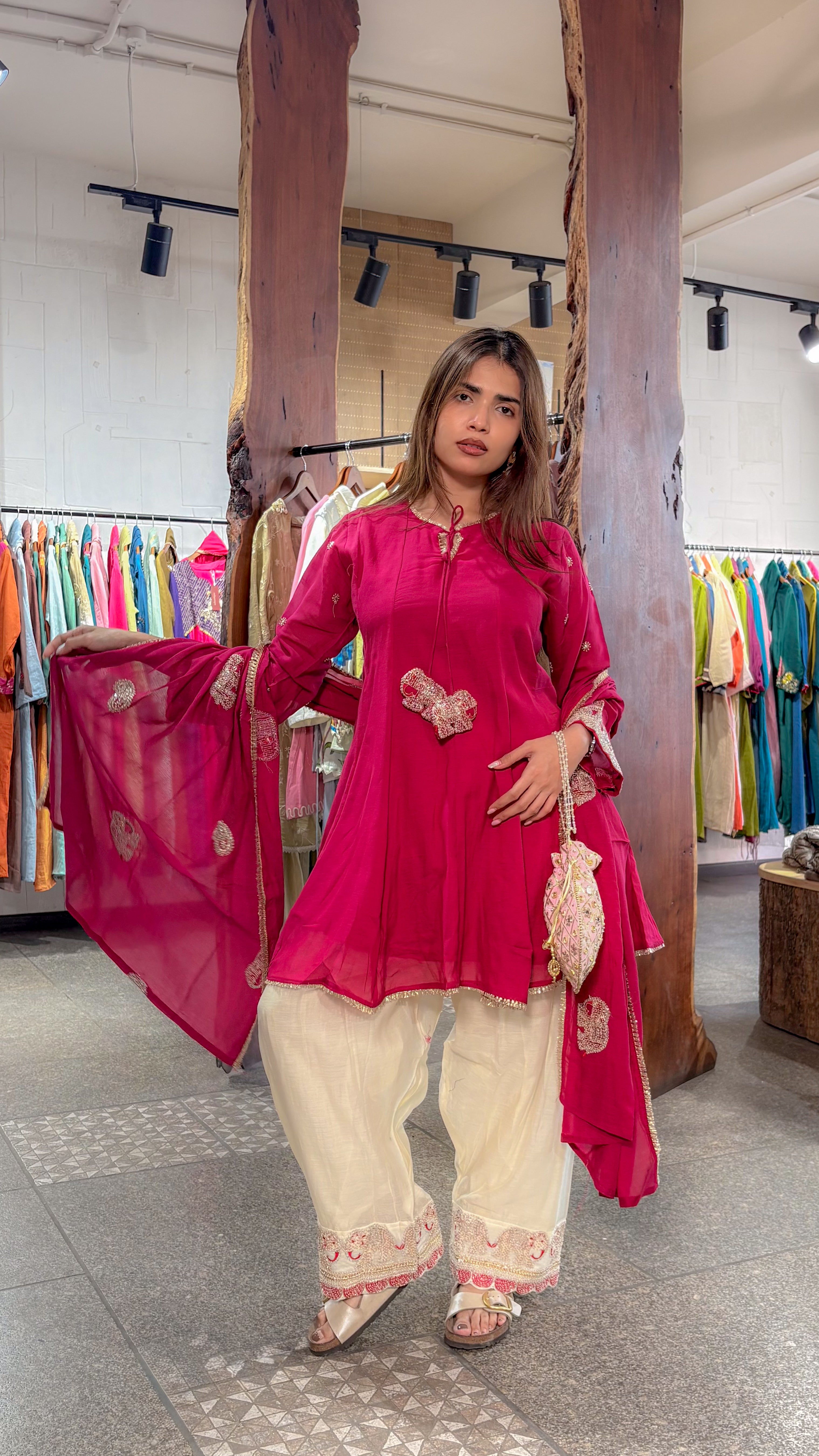 The rani dupatta held open beside the berry-toned frock kurta, with embroidery running along the ivory plazo hem.