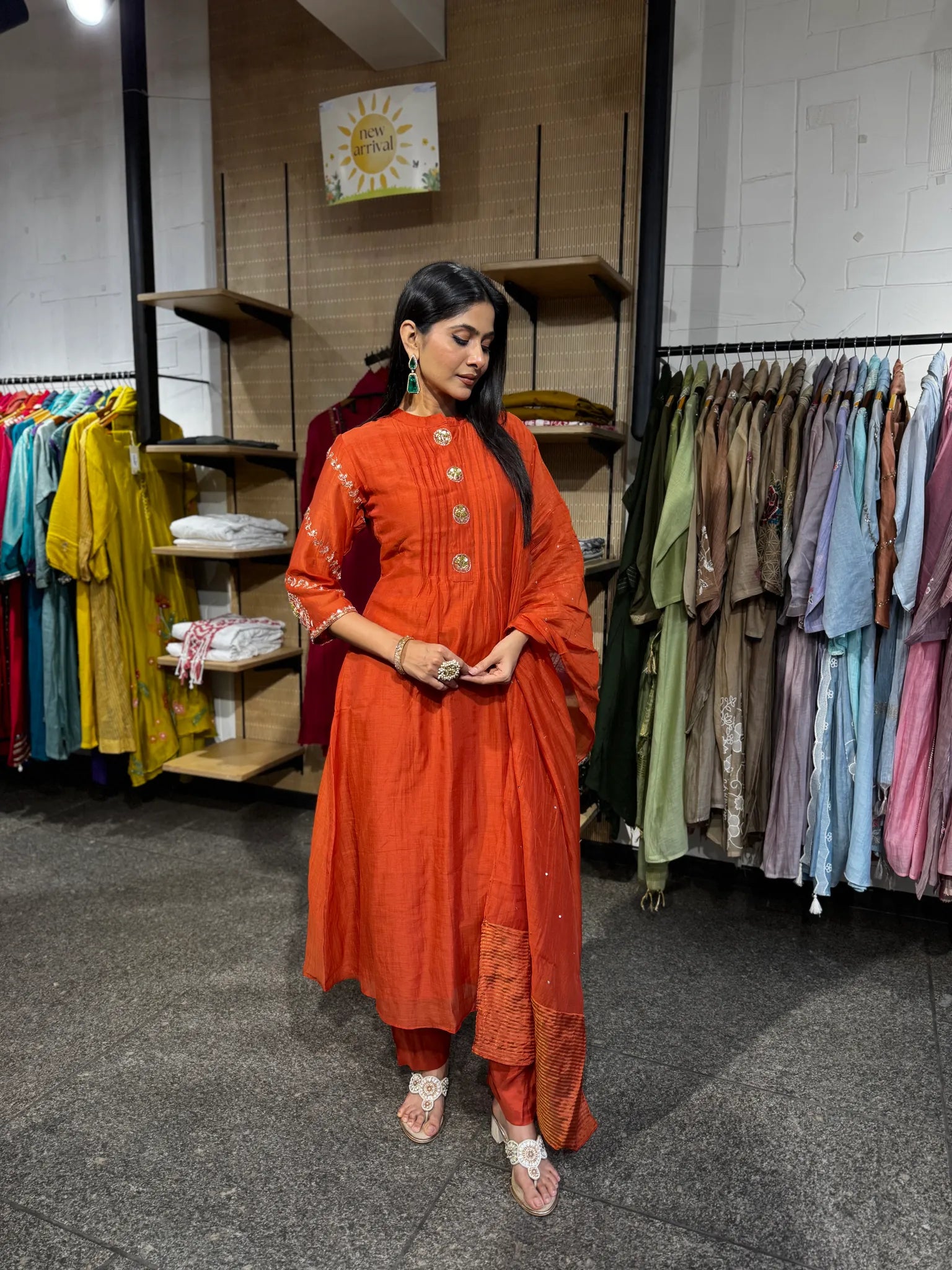 A woman wearing a rust orange mul chanderi A-line kurta and matching pants with the dupatta draped over one shoulder.