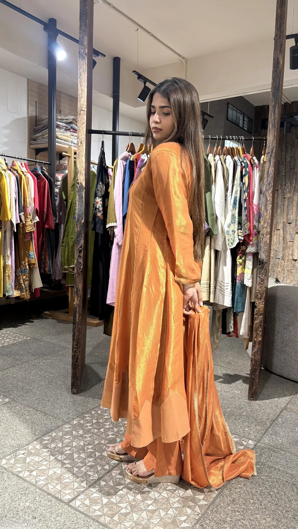 Three-quarter view of the rust orange kurta pant set, the amber tissue catching warm light along the sleeve and hem.