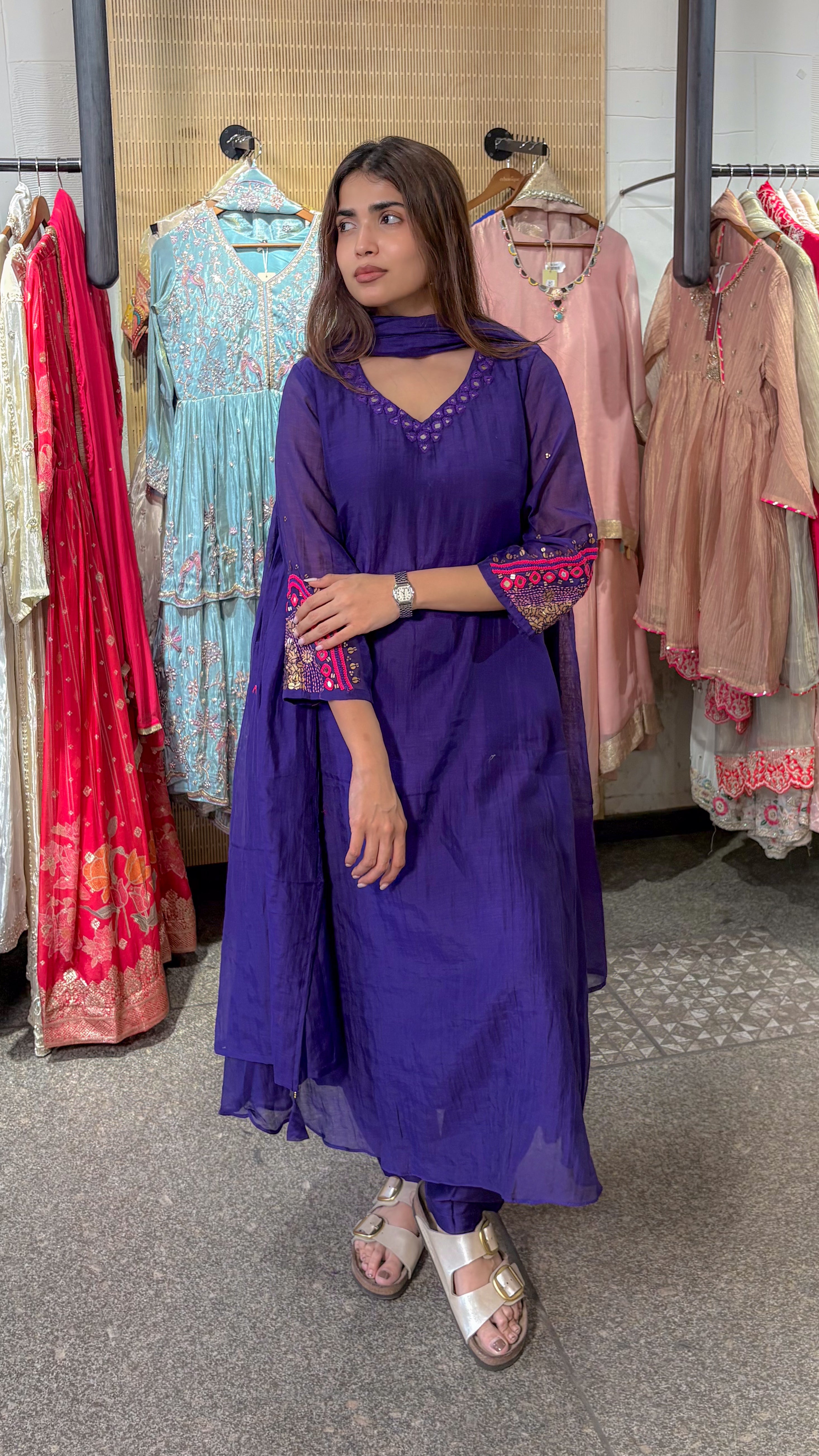 Side view of the violet kurta set, with pink and gold thread embroidery worked across the flared sleeve cuff and the neckline.