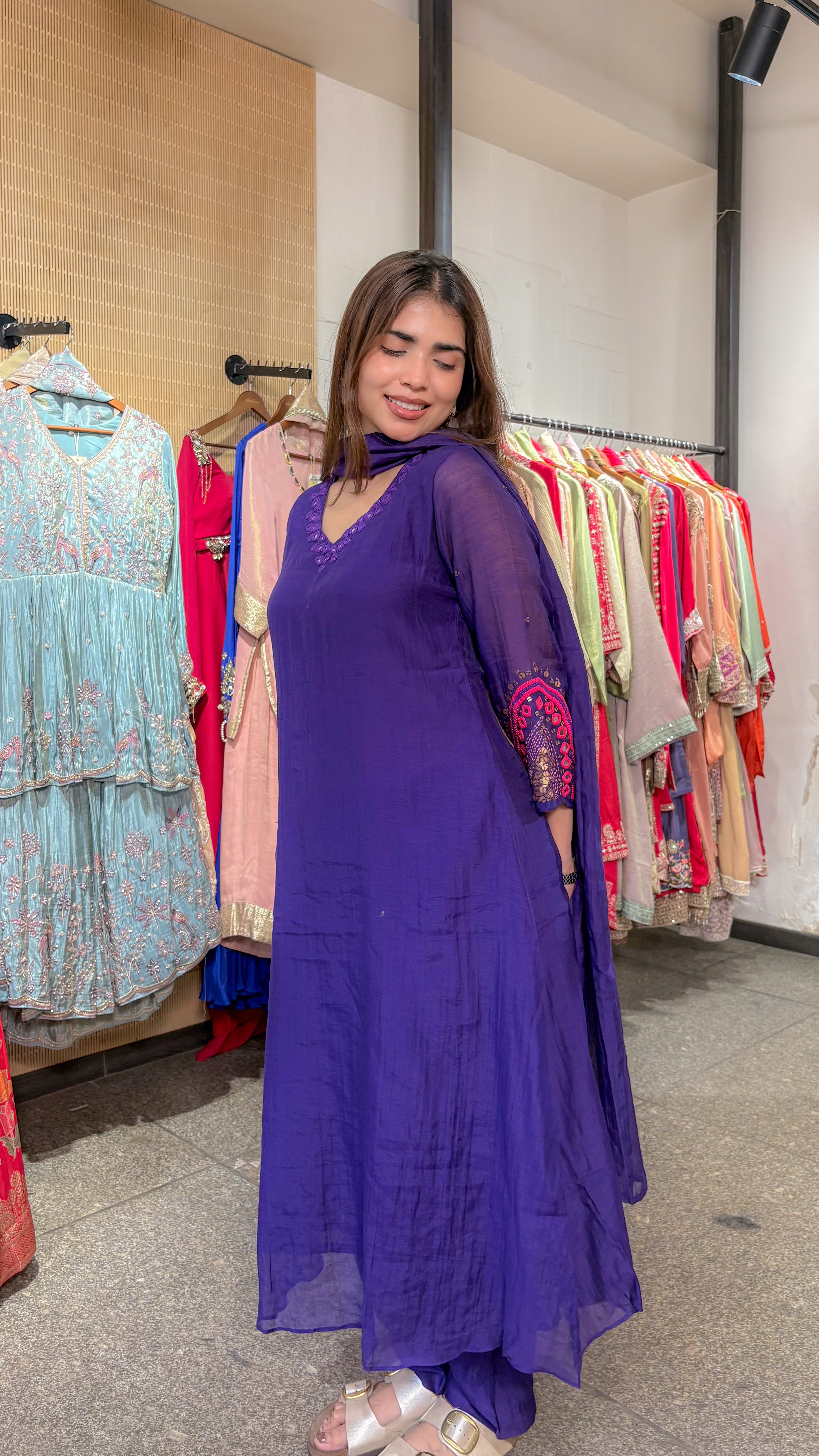 Three-quarter view showing the A-line fall of the violet mul chanderi kurta and the embroidered detail on the sleeve.