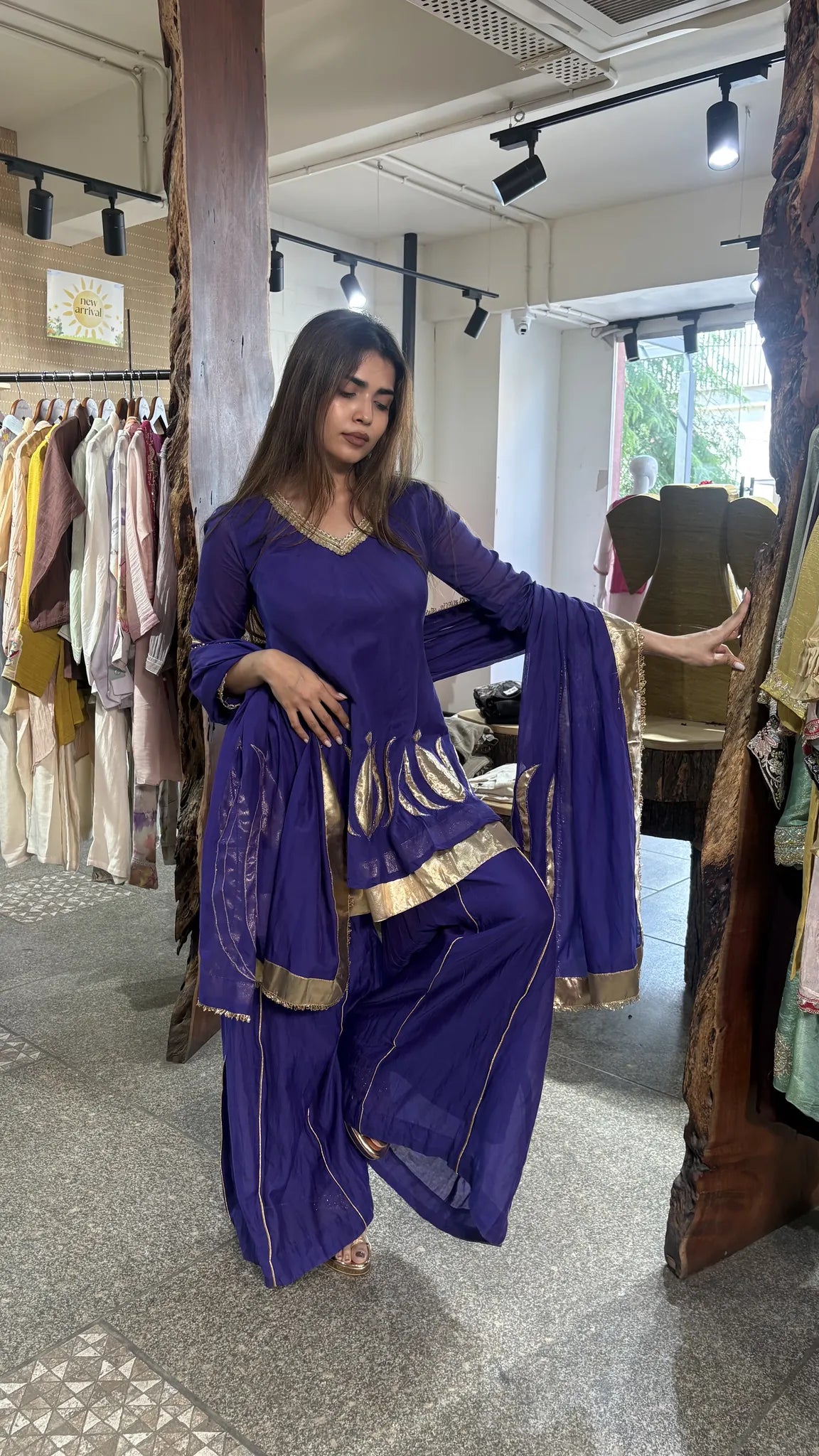 Mid-step in the violet plazo set, the wide gold-banded hem and gold leaf motifs on the kurta catching the light.