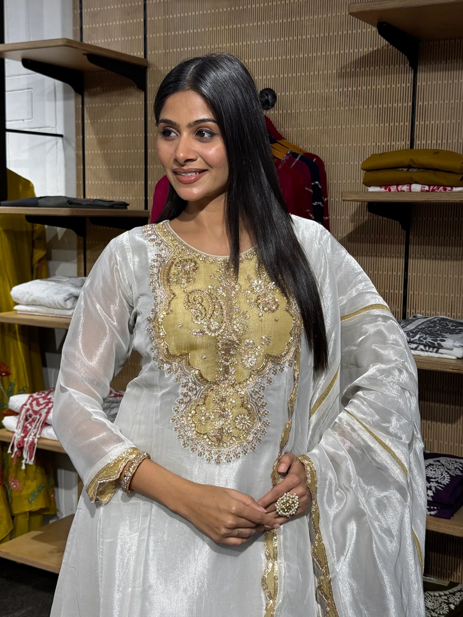Close view of the gold embroidered round neck yoke on a white tissue A-line kurta, worn with a sheer gold-bordered dupatta.