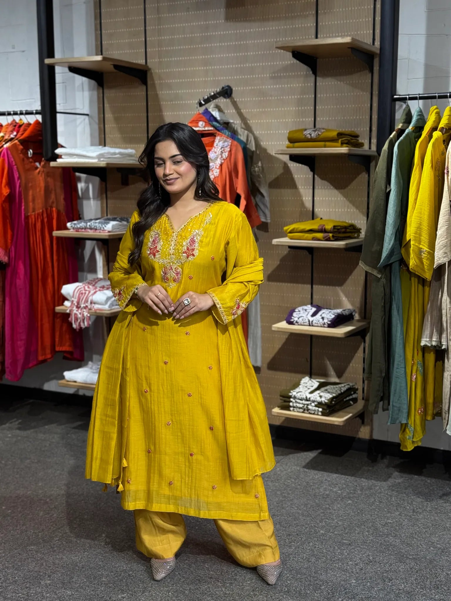 Full-length mustard silk set, model mid-step with the dupatta looped at her waist, small buti dotting the skirt.