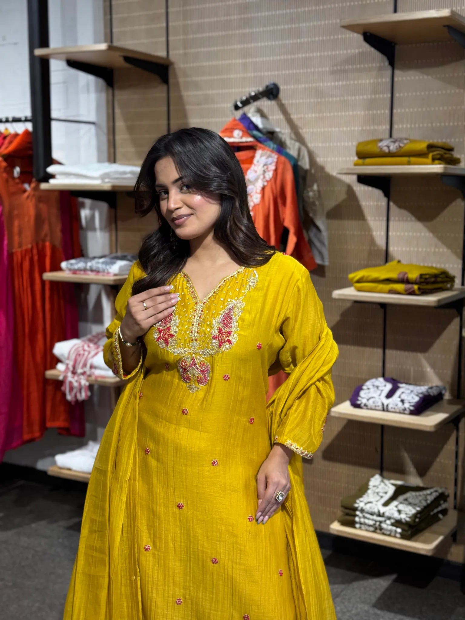 Close view of the mustard kurta's V-neck yoke, worked in dense pink floral embroidery outlined with ivory thread.
